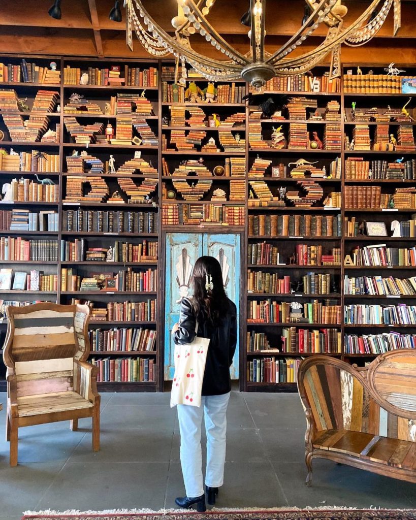 girl standing in front of verbatin books sculpture