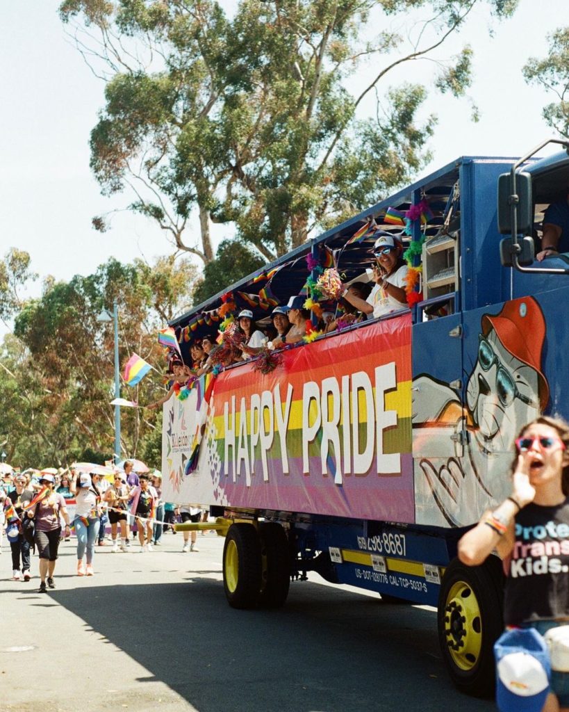 Bus with people on it with Pride Sign on the side of bus