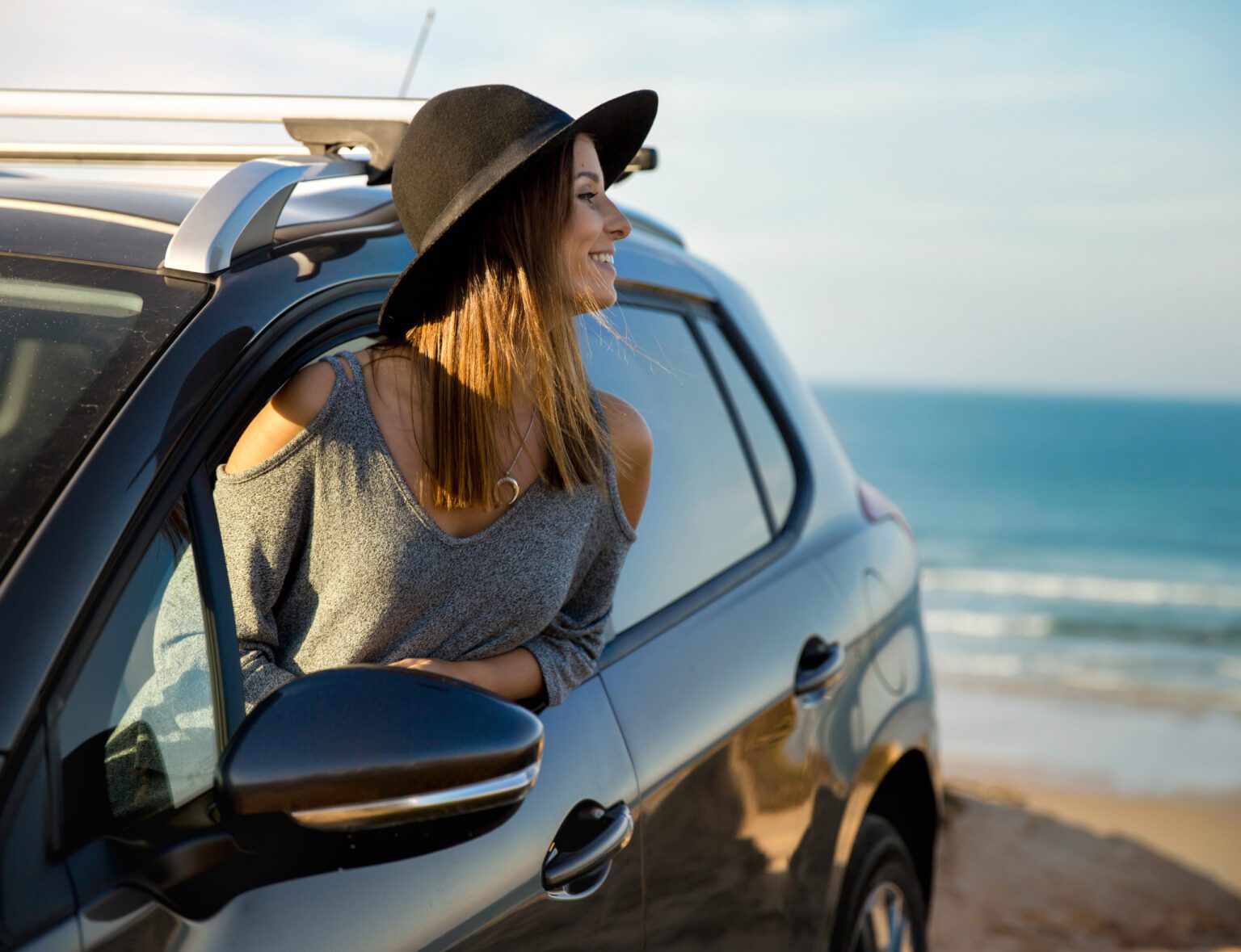 a woman looking out of her car window at the beach