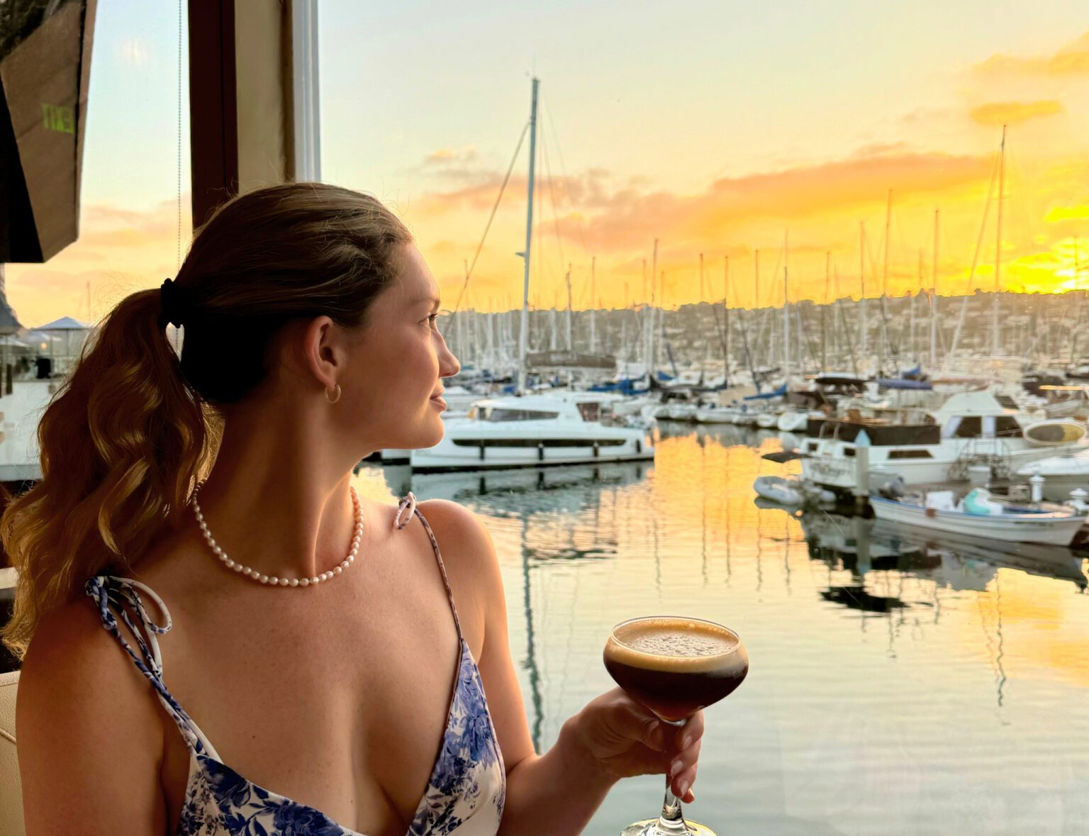 woman drinking wine, overlooking the marina