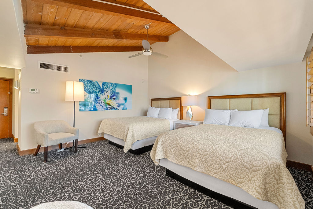 Two queen beds with a chair and lamp