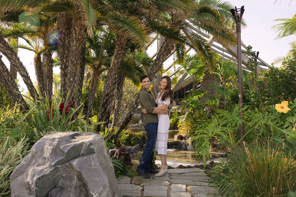 Couple holding each other in front of palm trees