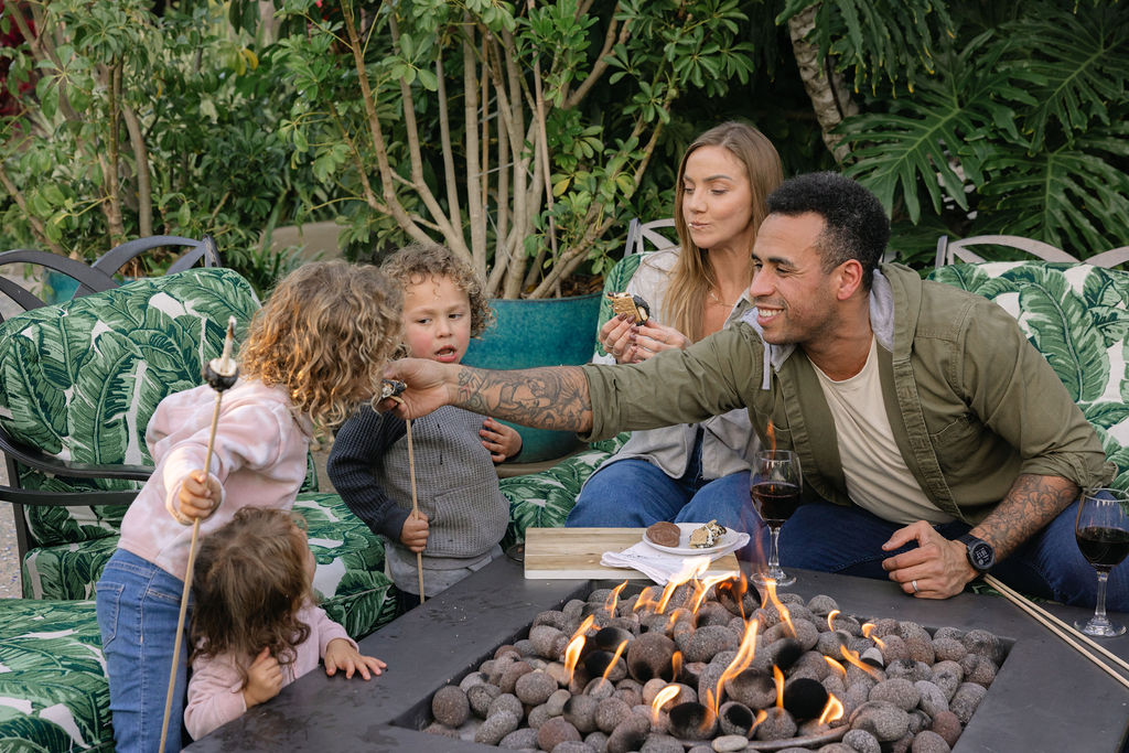 Family sitting around fireplace enjoying s'mores during San Diego Kids Free October