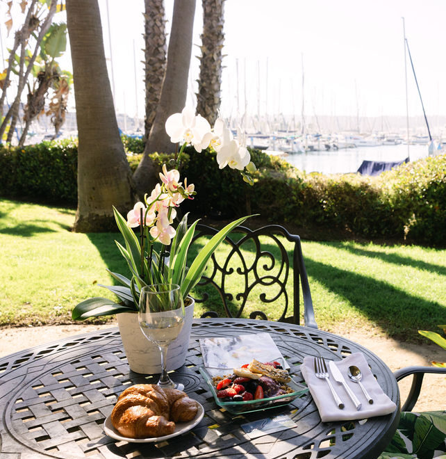 Bay & Breakfast package: croissant and acai with wine on outdoor patio, with marina views
