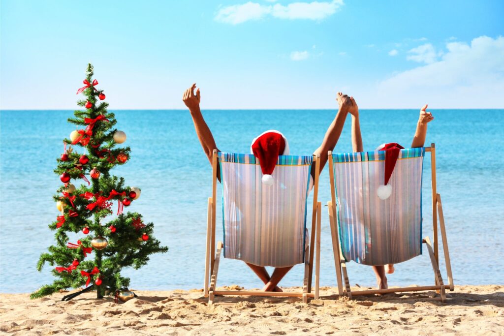 Two people sitting on beach chairs with a Christmas tree