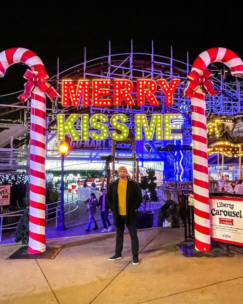 guy standing in front of candy canes and christmas sign