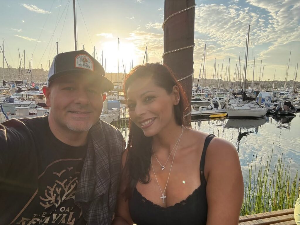 couple taking selfie with marina behind them