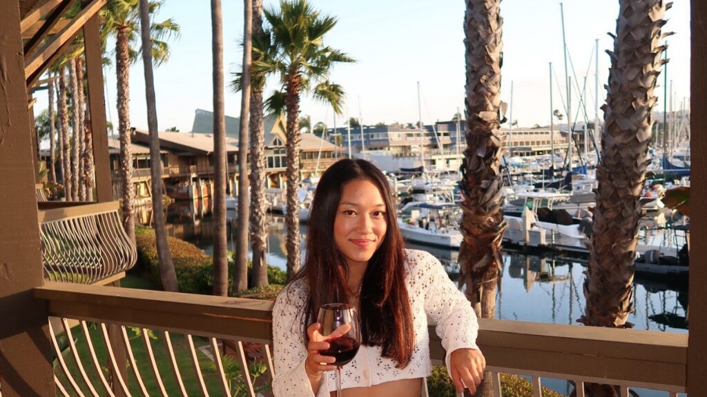 girl standing by marina with glass of wine