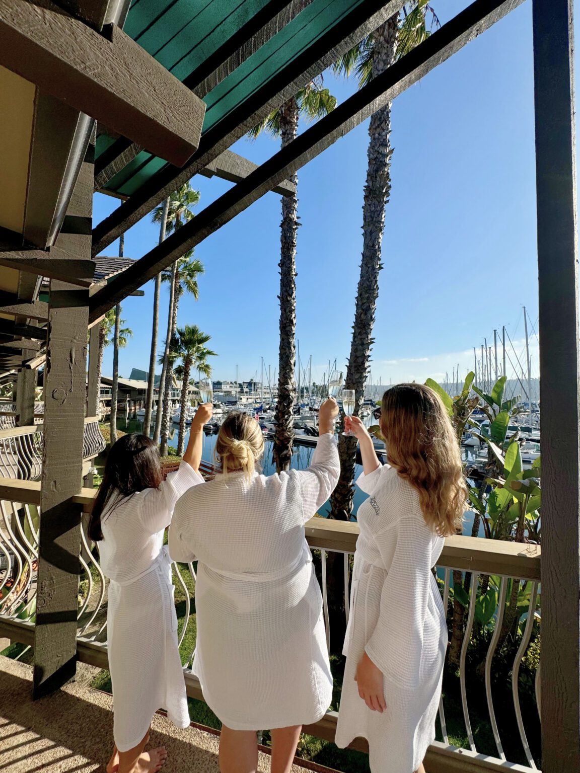 Girls standing on a balcony cheersing champagne